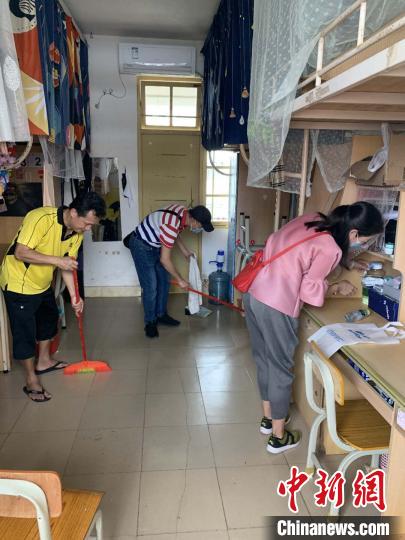 海南大学教师为学生打扫宿舍卫生。海南大学供图 点击进入下一页